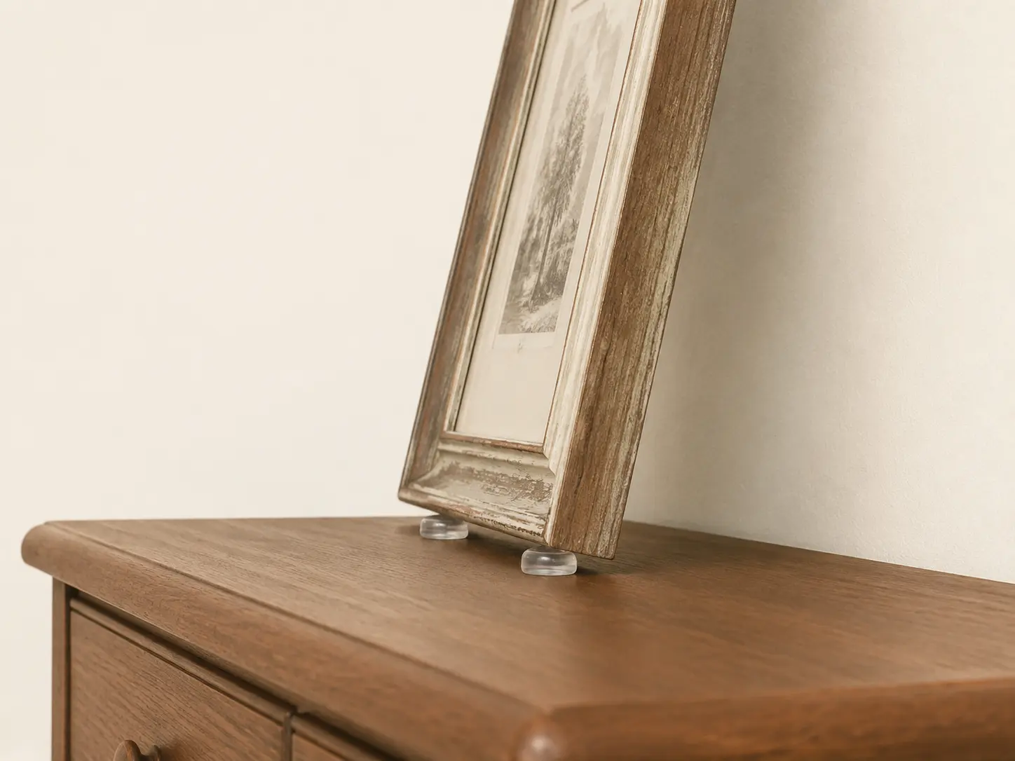 Angelehnter Vintage-Rahmen mit transparenten Rutschstoppern auf einer Kommode